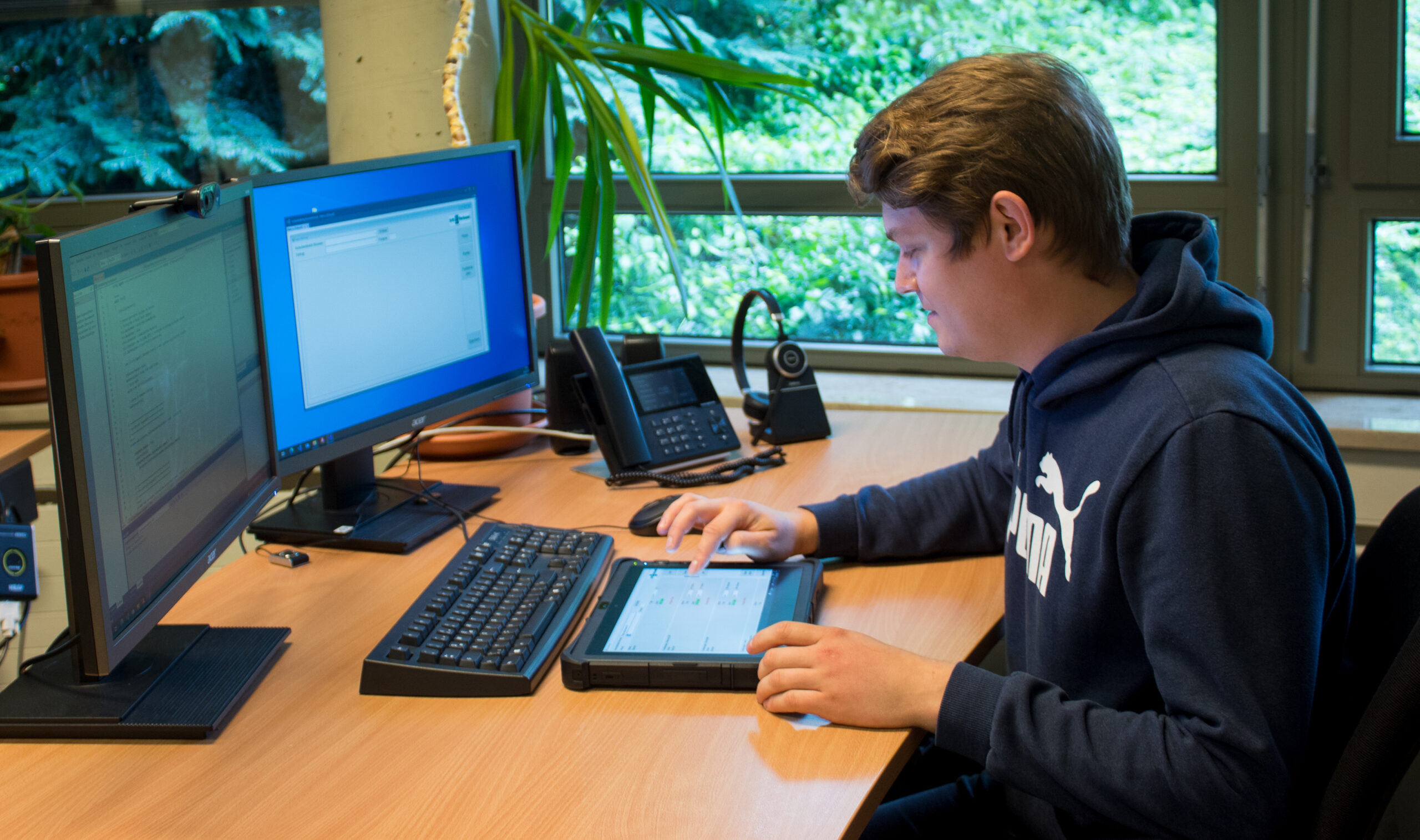 Werkstudent sitzt am Schreibtisch und bendient ein Tablet
